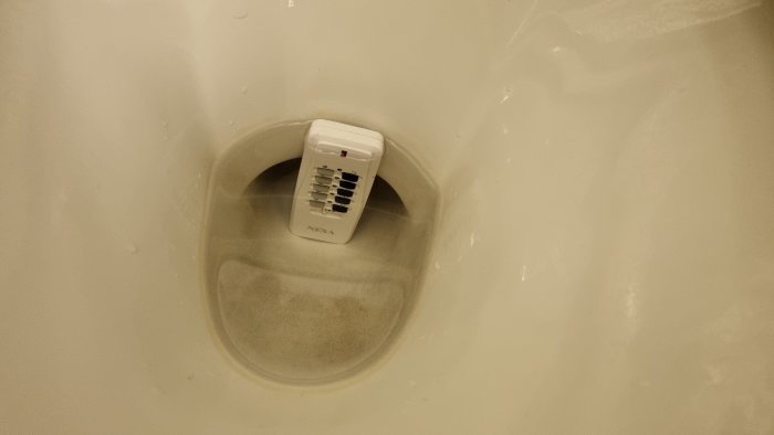En vit Nexa fjärrkontroll som ligger i en tom toalettstol.