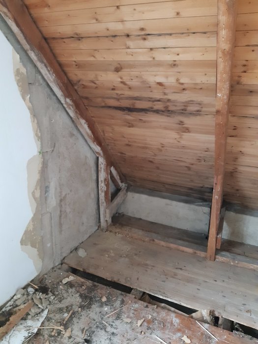 Interiör av en vind med träkonstruktion och isolering innan renovering.