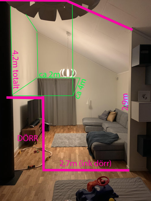 Vardagsrum med planerad vägg och loft i rosa och grönt, möbler och leksaker synliga.