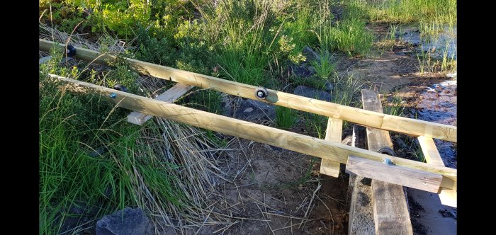 Hembyggd träbänk utomhus vid en strand med hjul för enkel förflyttning, gjord med material från byggvaruhus.