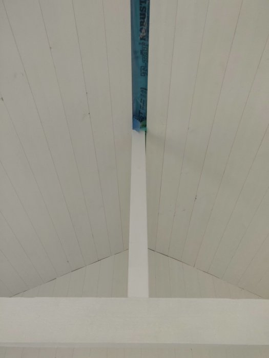 Vit panel på snedtak med en synlig springa längs taknocken.