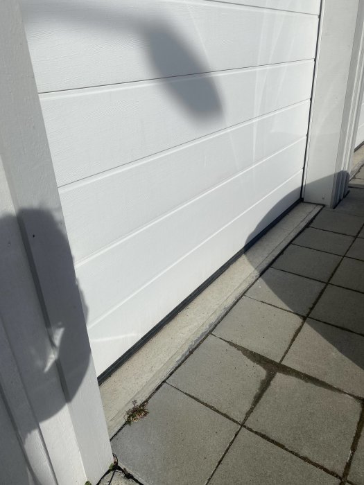 Vit garageport med tätlist längs golvet för att förhindra vattenintrång.