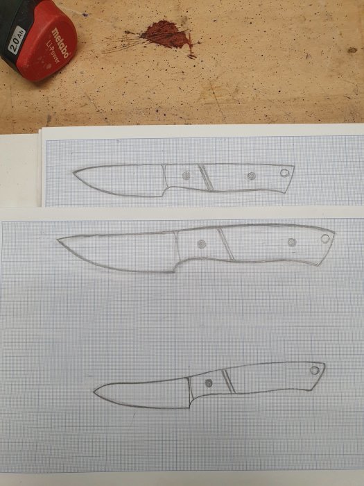 Två ritade knivar på rutat papper ovanpå en verkstadsbänk med sudd och röd mätare.