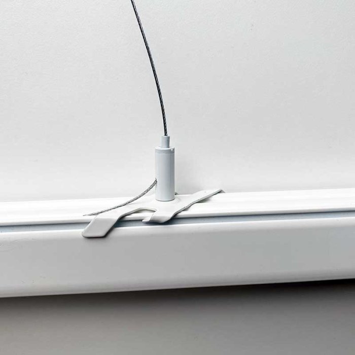 Belysningsskena på vägg med tillhörande eluttag och lampa ansluten via kabel och kopplingsdosa.