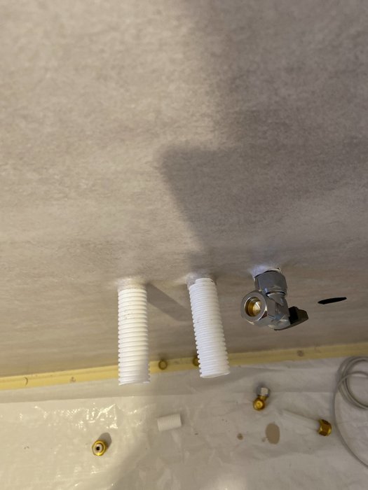 Väggbrickor och vattenrör monterade för nära väggen i ett badrum under renovering.