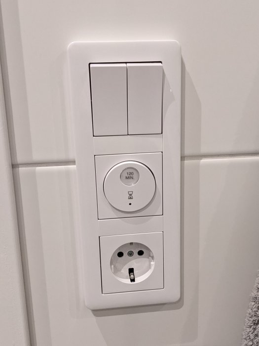 Väggmonterad timerinställd eluttag för handdukstorkar med 120-minuters knapp.
