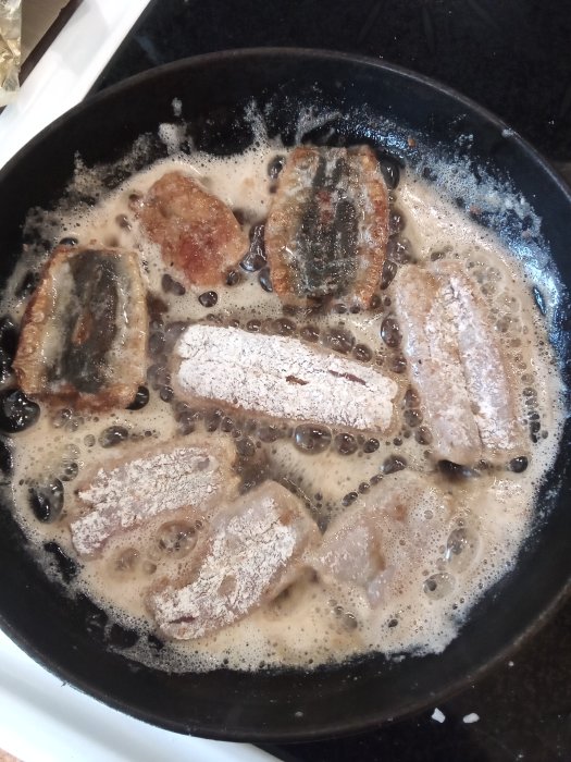 Stekt strömming i stekpanna med fräsande smör och kryddpeppar.