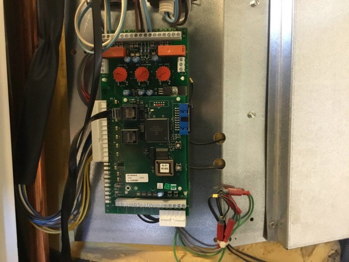 Interiör av en öppen frånluftsvärmepump som visar elektronikkort och kablarna inuti.