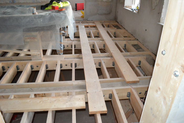 Bild av nykonstruerade trägolvreglar installerade i ett renoveringsprojekt, redo för gjutning av betong.