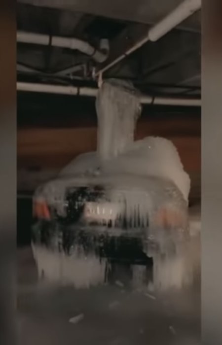 Vattenledning med omfattande isbildning som hänger från ett innertak.