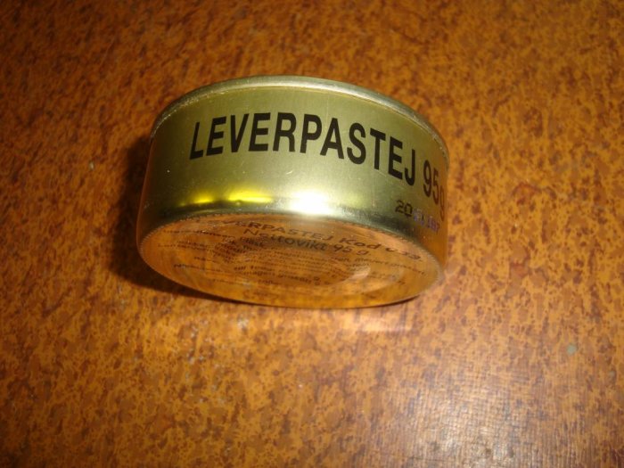 Gammal burk med texten "LEVERPASTEJ 95g" på ett rostfläckat brunt bord.