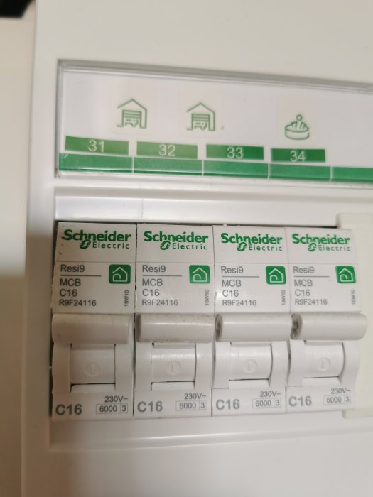 Elektriskt säkringsskåp med fyra Schneider Electric säkringar och numrerade positioner över dem.