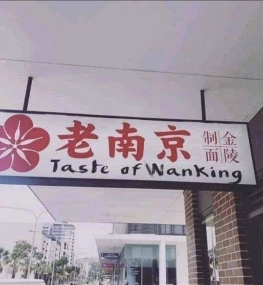 Skylt med kinesisk text och engelsk översättning "Taste of Wanking" hängande utanför byggnad.