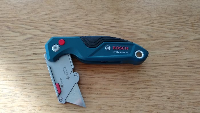 Bosch Professional hopfällbar kniv med utbytbart blad på träbord.