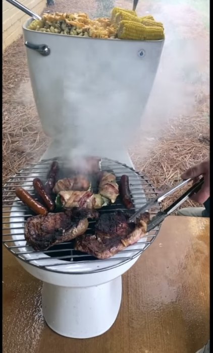 Grillning på en omvänd toalett fylld med kol, kött och majskolvar på locket som används som grillgaller.