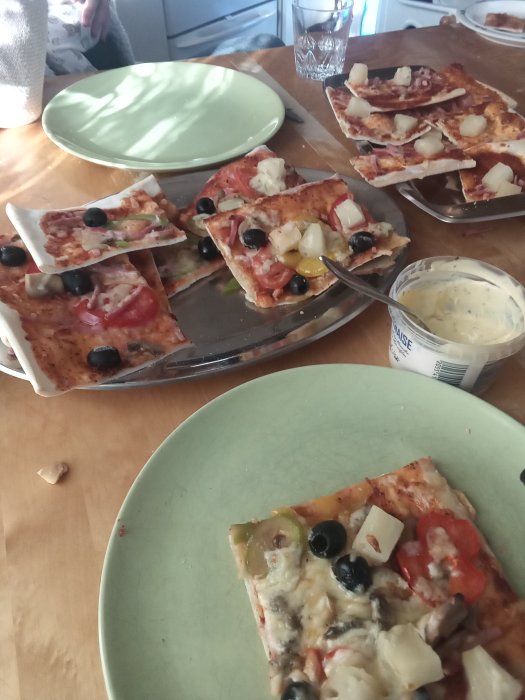 Hemlagad pizza med olika pålägg och en skvätt sås på tallriken, otydlig bakgrund.