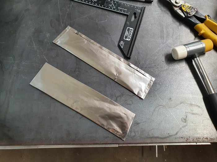 Blad inslagna i värmetålig folie med verktyg för härdning: vinkelhake, sax och gummihammare.