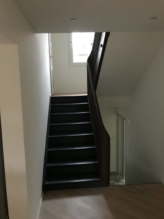 Trappa i trähus med svarta steg och vitmålade väggar som knarrar.
