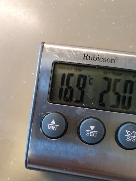 Digital kökstermometer som visar 150°C på ett köksbord.