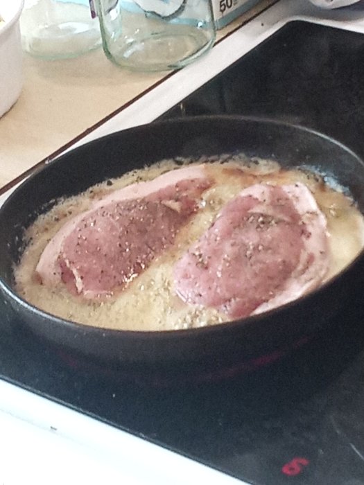Fläskstek med pepparkryddor steks i panna med smör och olja, redo att ösas.