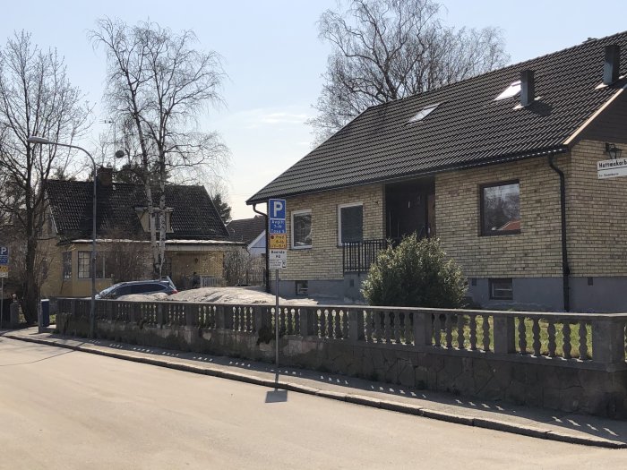 Gammalt betongstaket med pelare och djur-reliefer framför ett hus från 60-talet.