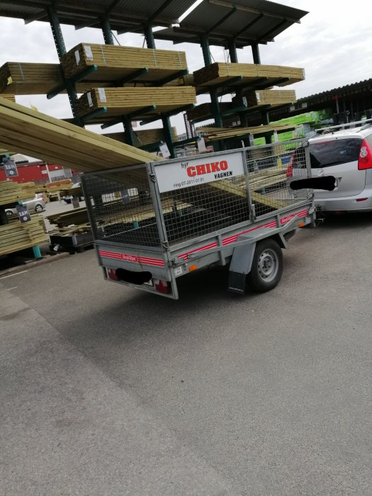 Släpvagn lastad med trävirke, spännbandet dras felaktigt över lasten utan att vara loopsurrat.