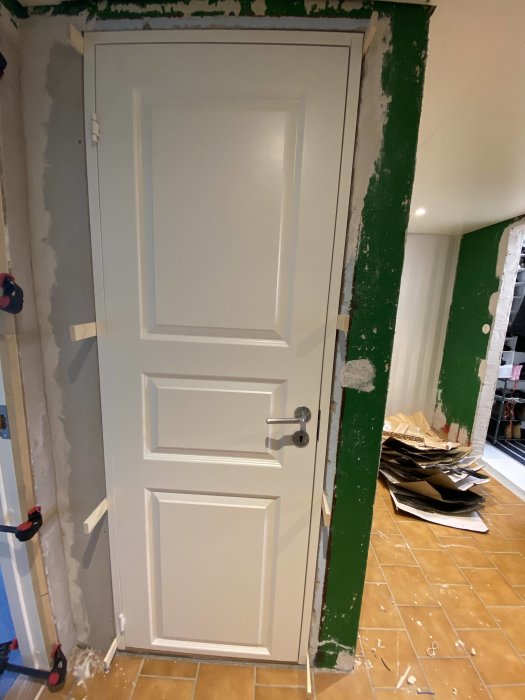 Nyinstallerad vit innerdörr i ett pågående renoveringsprojekt med synliga byggmaterial och verktyg.