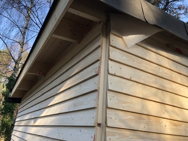 Hörnet av ett bygge med nyinstallerad fjällpanel och spikläkt uppe och nere på en byggnad.