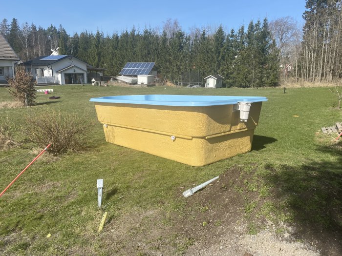 Nyinstallerad ovanmarkspool i trädgården med omgivande grönska och hus i bakgrunden.