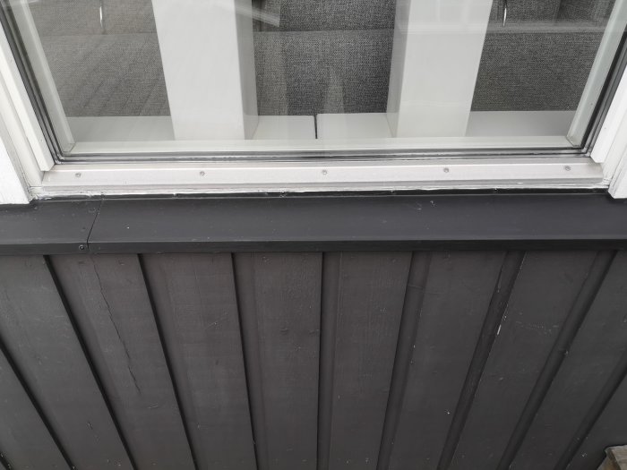 Detaljbild av ett fönster med ett metallbleck vid fönsterbänken som eventuellt är ett droppbleck.