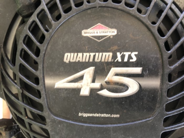 Närbild av Briggs & Stratton Quantum XTS 45 gräsklipparmotor med logotyper och modellbeteckning.