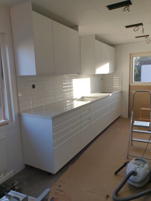 Vit köksinredning med komposit bänkskiva i marmormönster, under installation.