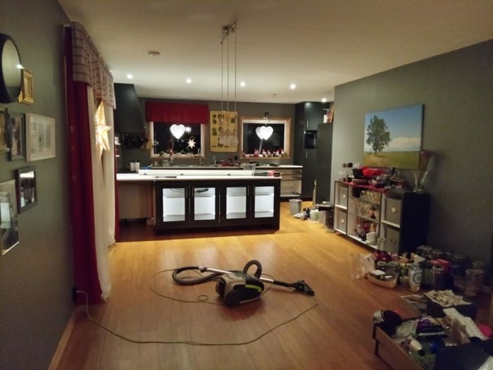 Kök under renovering med öppna skåp och verktyg på golvet; renoveringsprocess synlig.