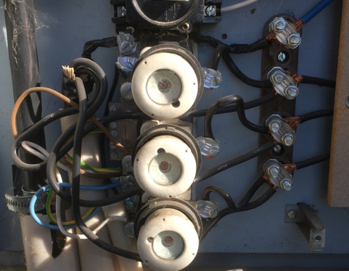 Öppnad mätarcentral med blandade elektriska kopplingar för fördelning till huvudbyggnad, garage och laddstation.