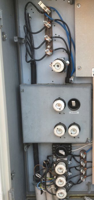 Mätarcentral med öppen lucka visar blandade kopplingar för huvudbyggnad, garage och laddstation.