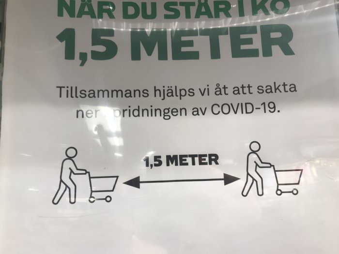 Skylt uppmanar till 1,5 meters avstånd med illustration av två personer med kundvagnar för att förhindra COVID-19 spridning.