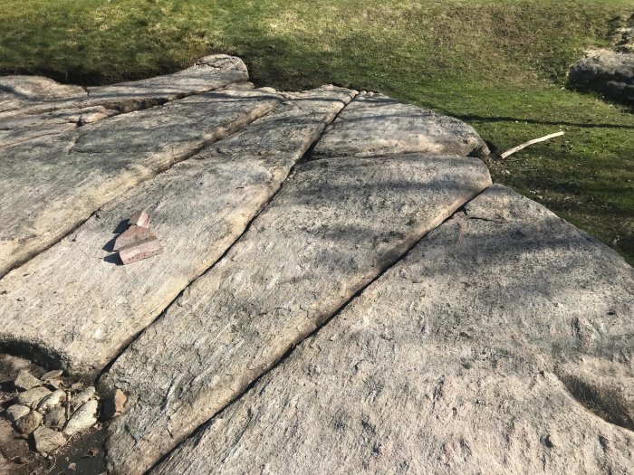 Rengjorda bergskrevor i trädgård efter högtryckstvättning mot grön gräsmatta.