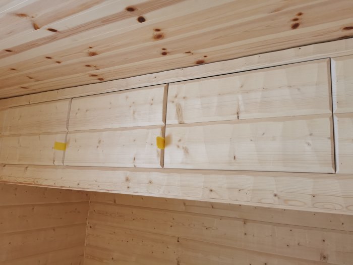 Hemmagjorda skåpluckor av bilad timmerpanel monterade på IKEA-skåpstommar mot trävägg.