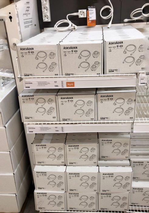 Försäljningshylla i butik fylld med ASKVÄDER elprodukter, priset 199:-, med nyhetsskylt.