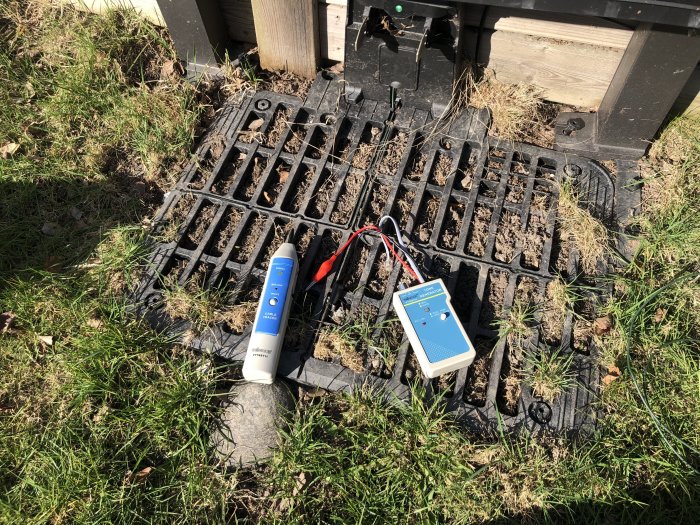 Elektronisk fuktmätare och marktäthetsmätare placerade på en brunnen markyta utomhus.