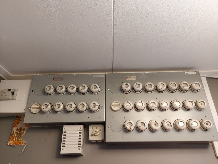 Elcentral med säkringar och knappar på en vägg i ett hus.