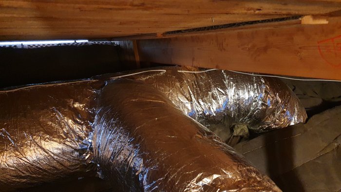 Isolerade ventilationsrör och flexibel dämpare genom ett takbjälklag.