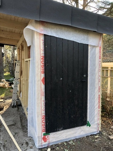 Svart dörr monterad på en byggnad under konstruktion innesluten av byggplast.