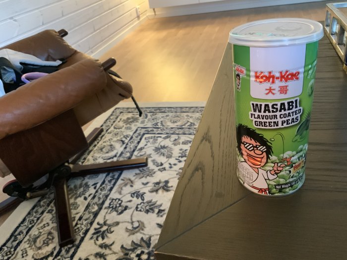 Burk med wasabi-flavoured gröna ärter på ett träbord bredvid en soffa och matta.