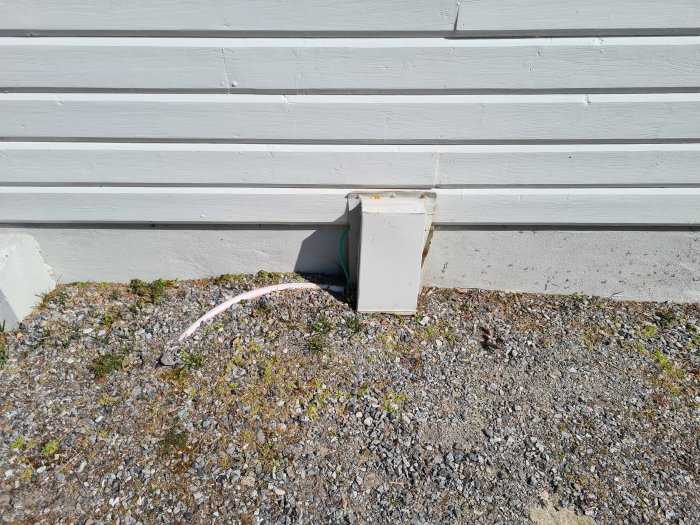 Osäker elektrisk kabelanslutning utsatt vid husvägg med oskyddade kablar och öppet anslutningsuttag.