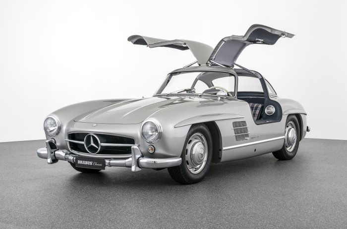 Silverfärgad Mercedes-Benz 300 SL med öppna måsvingedörrar i en studio.