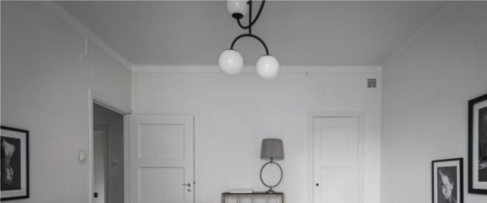Interiör av en klassisk lägenhet med vitmålade väggar, rundat tak utan lister och en lampa som hänger från taket.