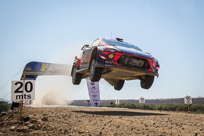 Rallybil hoppar i luften över en ramp på en grusväg under en rallytävling.