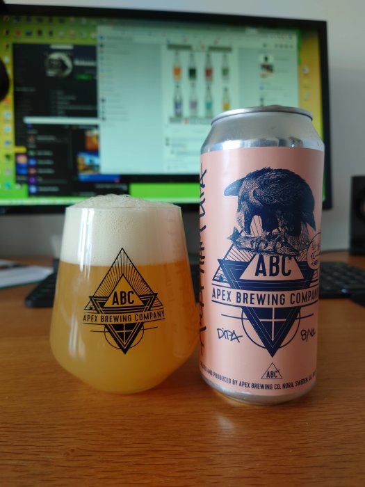 Apex Brewing Company ölburk och glas med skummad öl framför en datorskärm.