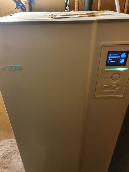 Nibe bergvärmepump F1126 med digital panel visar inställningar, placerad inomhus.